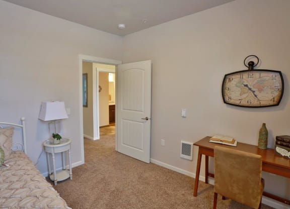 a bedroom with a bed and a desk with a clock