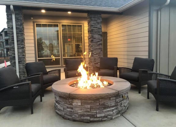 a fire pit on the patio of a home with chairs