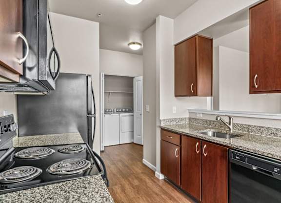A kitchen with a black stove top oven and wooden cabinets.