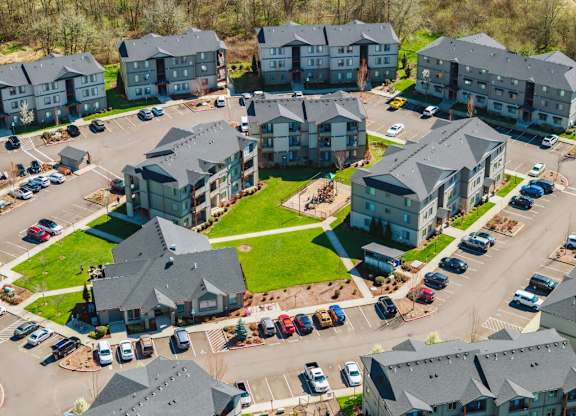 A bird's eye view of a parking lot with cars and apartment buildings.