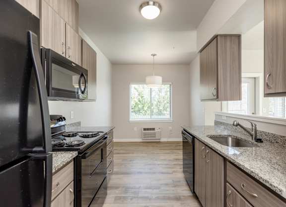A kitchen with black appliances and wooden cabinets.