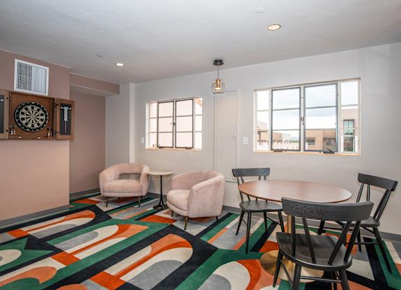 A room with a dart board on the wall and a colorful carpet.