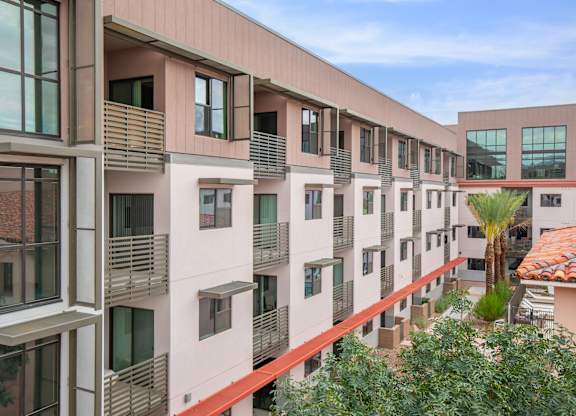 A modern apartment building with balconies and a red roof.