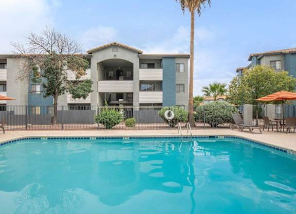 A swimming pool in front of a building with a palm tree.