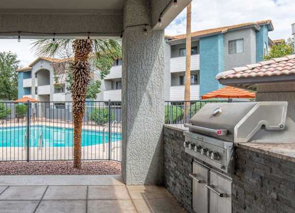 A grill is on a patio next to a pool.