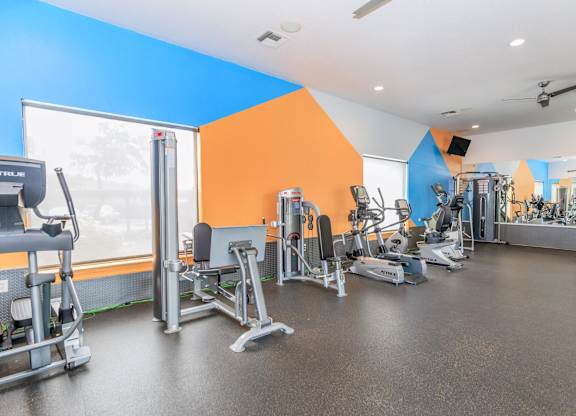 A gym with a variety of equipment including treadmills, weights, and exercise machines.