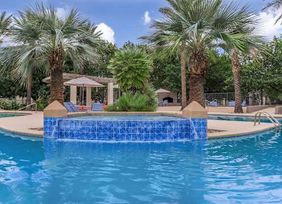 A pool surrounded by palm trees and a gazebo.