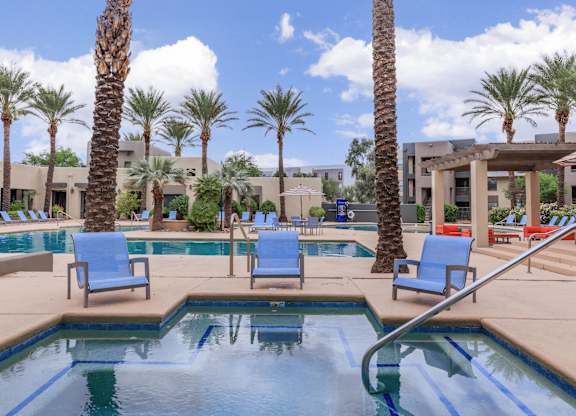 A pool surrounded by palm trees and lounge chairs.