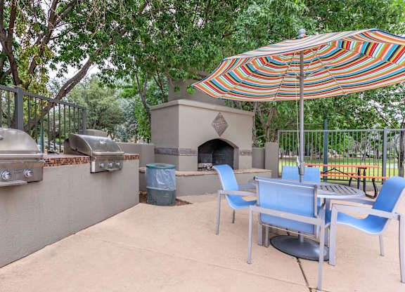 A patio with a table, chairs and an umbrella.
