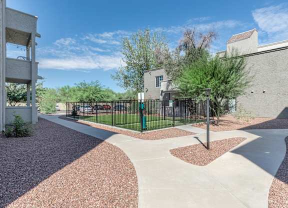 A modern courtyard with a black fence and a mix of red and grey gravel.