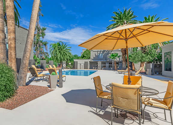 A patio with a table and chairs and a pool in the background.