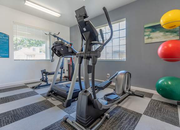 A gym with a treadmill, exercise ball, and other equipment.