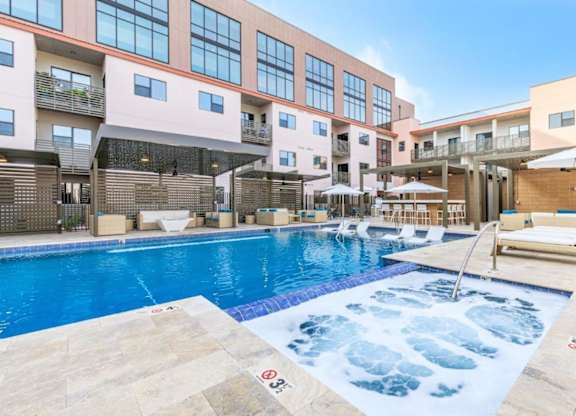 A large outdoor swimming pool with a hot tub in the middle of it.