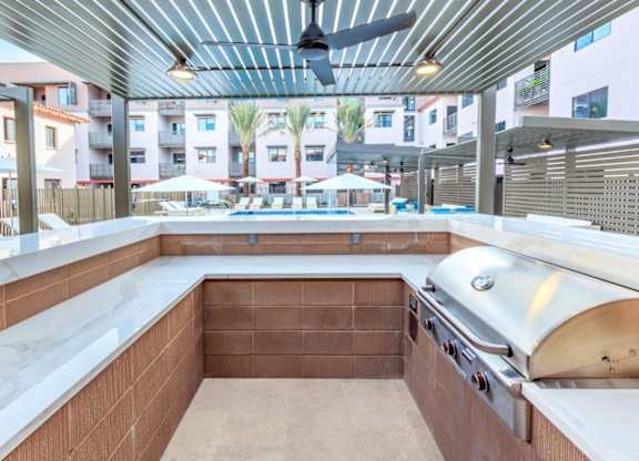A modern outdoor kitchen with a built-in grill and seating area.