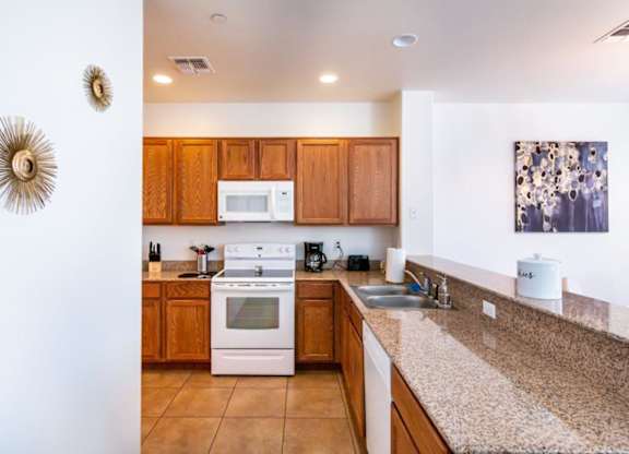 A kitchen with a white stove top oven and wooden cabinets.