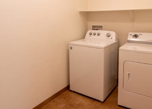 Two white front loading washing machines in a laundry room.