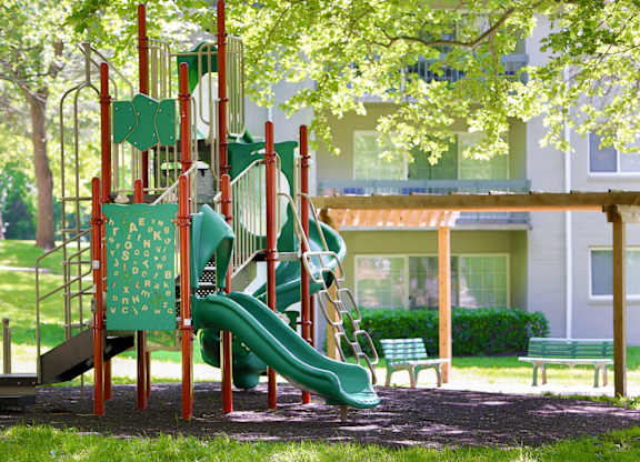 A playground with a green slide and a red structure.