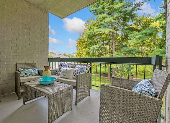 A patio with a table and chairs with a view of trees.
