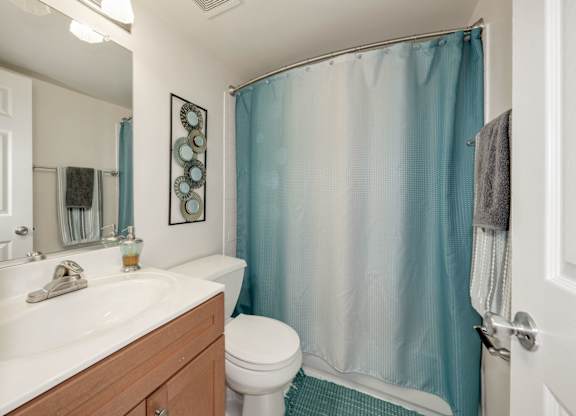 A bathroom with a white sink, toilet, and a blue shower curtain.