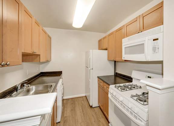 A kitchen with white appliances and wooden cabinets.