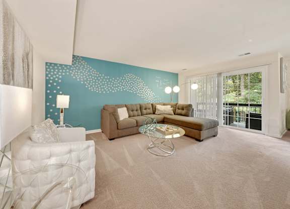 A living room with a white sofa and a glass coffee table.