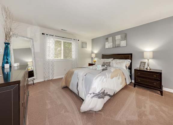 A bedroom with a large bed and a nightstand with a lamp.