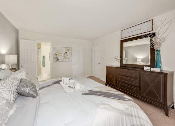 A bedroom with a large bed and a wooden dresser.