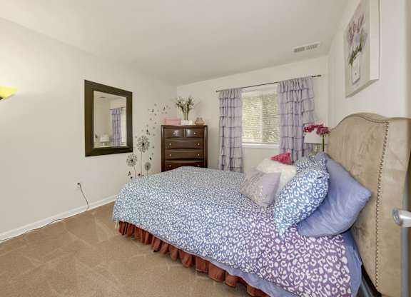 A bedroom with a bed, nightstand, and lamp.