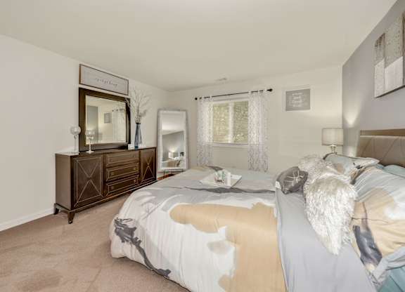 A bedroom with a bed, nightstand, and dresser.