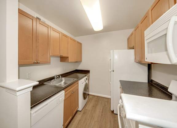 A kitchen with white appliances and wooden cabinets.