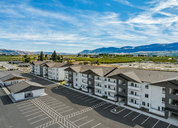 A parking lot in front of apartment buildings with a mountain range in the background.