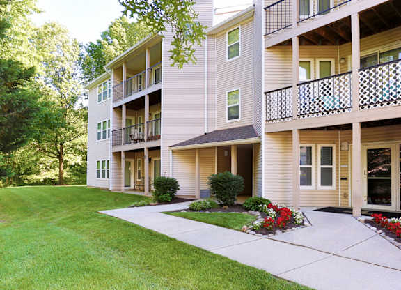 A building with a balcony and a green lawn in front.