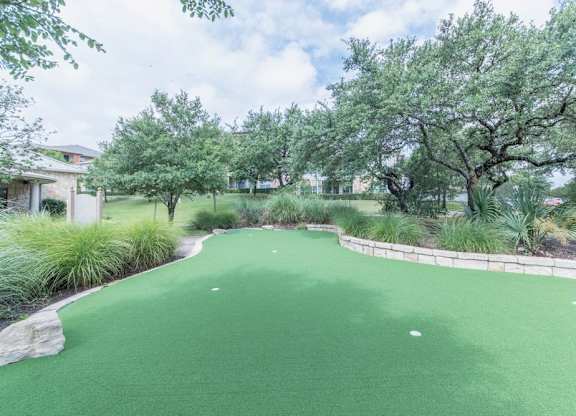 A green artificial turf area surrounded by trees and plants.