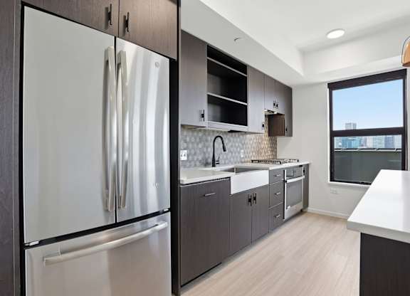 A modern kitchen with a stainless steel refrigerator and wooden cabinets.