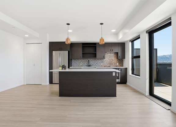 A modern kitchen with a large island and pendant lights.