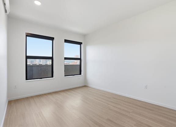 A room with two windows and wooden flooring.