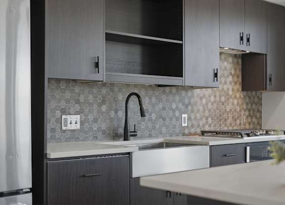 A modern kitchen with a white countertop and dark grey cabinets.