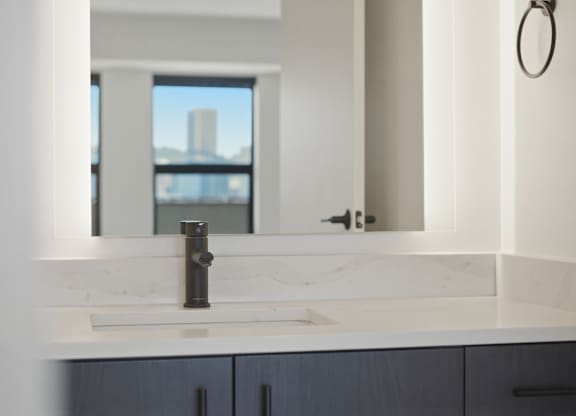 A bathroom sink with a marble counter top and a large mirror.