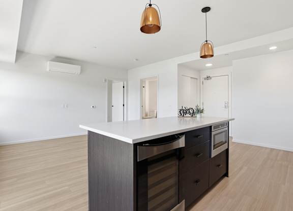 A modern kitchen with a large island and dark wood cabinets.