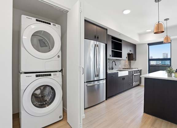 A modern kitchen with a washer and dryer built into the cabinetry.