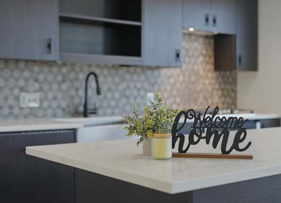 A kitchen counter with a vase of flowers and a sign that says