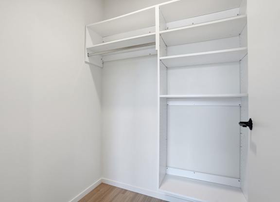 A white door is closed in a white room with a bunk bed.