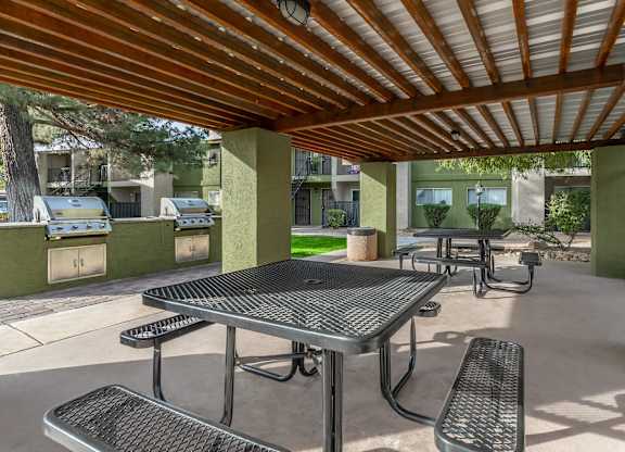 A patio with a table and chairs under a roof.
