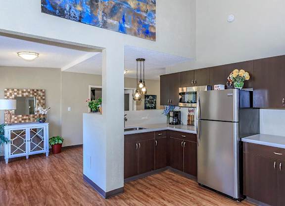 A kitchen with a refrigerator, sink, and wooden floors.