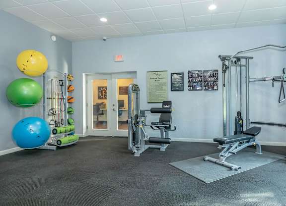 A gym with a variety of equipment including a leg press machine, a bench press, and a squat rack.