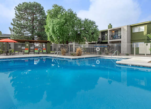 A swimming pool in front of a building with a fence around it.