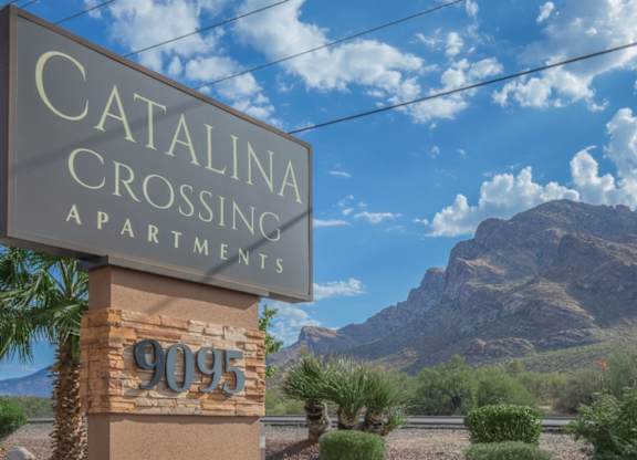 A sign for Catalina Crossing Apartments stands in front of a mountain.