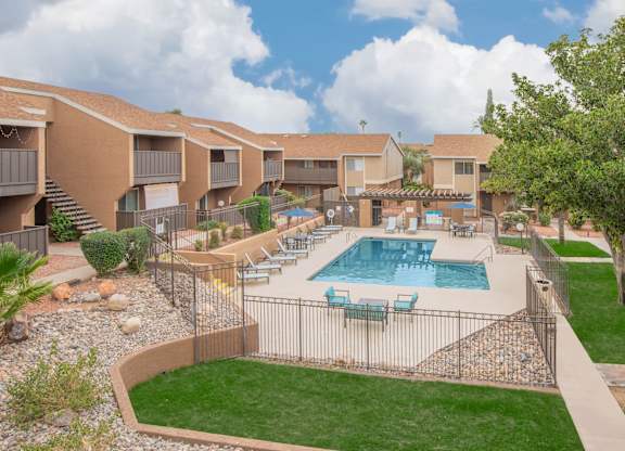 A swimming pool surrounded by a fence and chairs.
