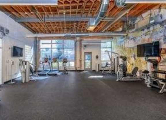 A spacious gym with various exercise equipment and a large mirror on the wall.
