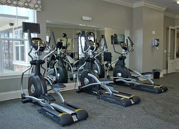 A gym with a row of stationary bikes.